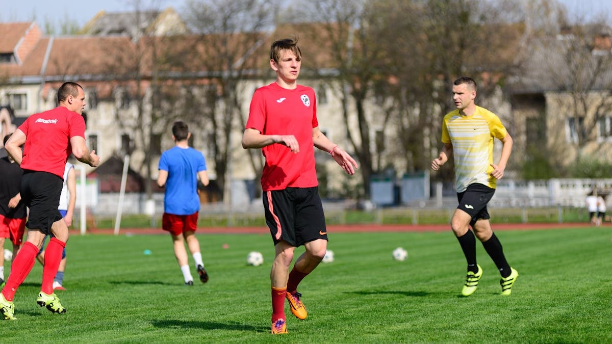 Young men practicing soccer on a sunny day at an outdoor field, focusing on exercise and teamwork.
