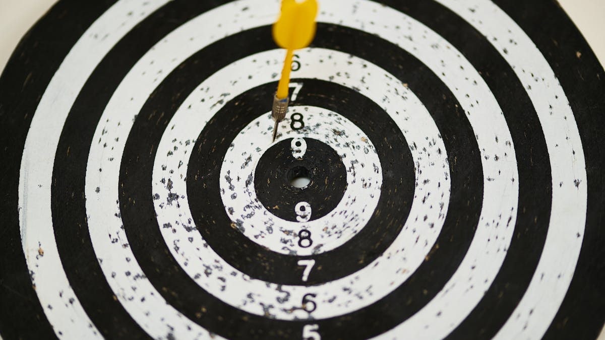 Close-up of a dart hitting the bullseye on a black and white target board symbolizing success.